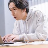 眉間に皺を寄せながらPC操作をする男性